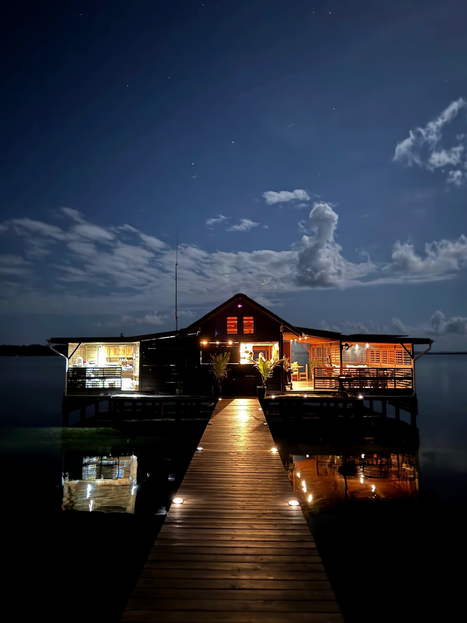 Blå Bar & Restaurant at night, boardwalk lights reflecting on the water in Dolphin Bay
