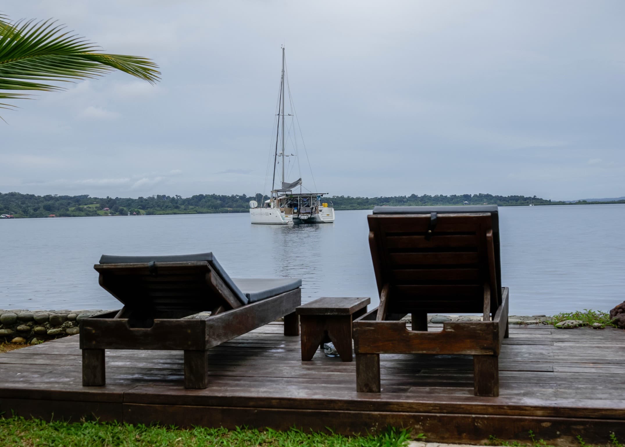 Lounge chairs on waterfront deck with catamaran view at Dolphin Blue Paradise, Bocas del Toro - perfect for sunbathing