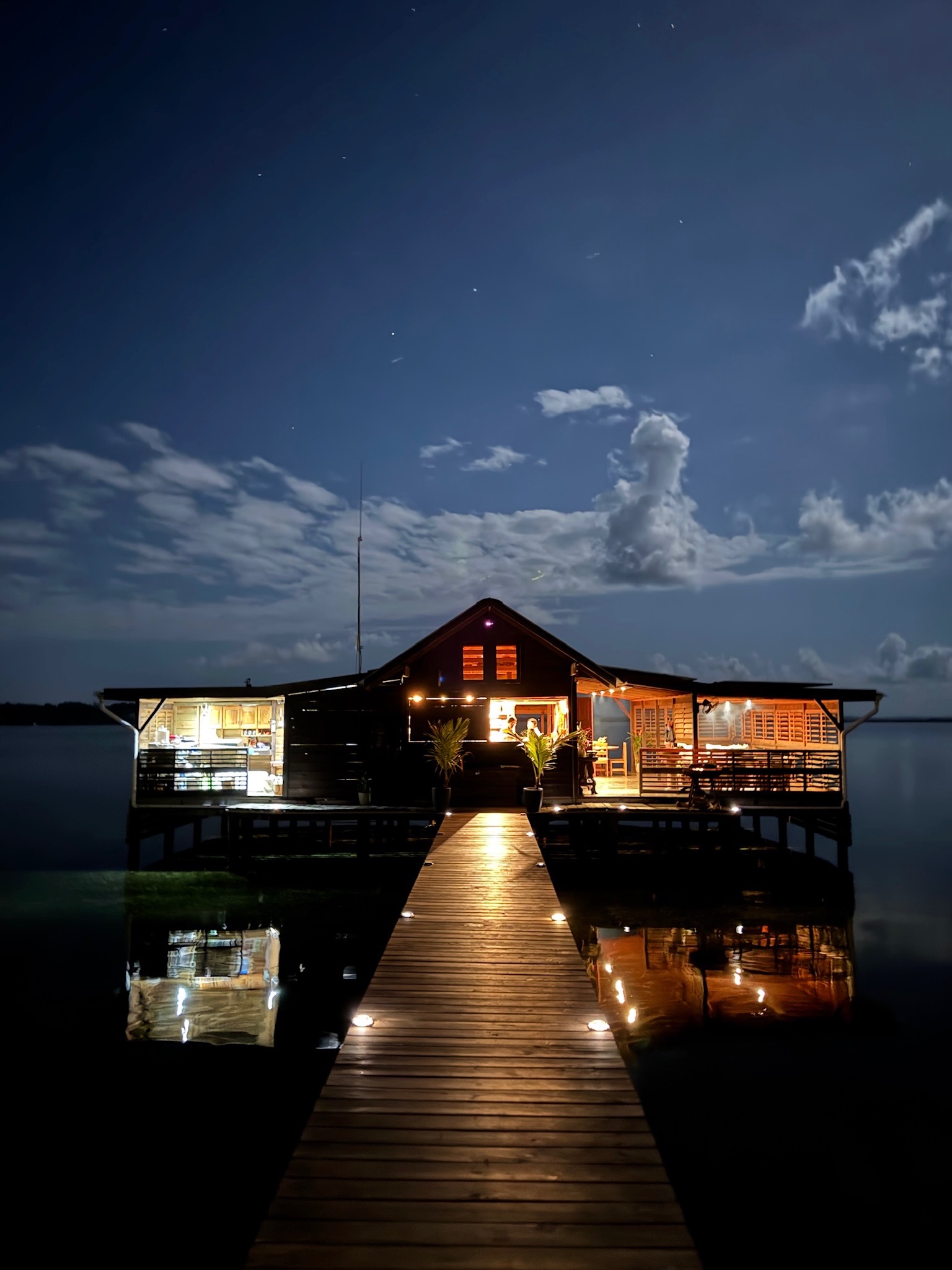 Blå Bar & Restaurant de noche, con el muelle iluminado sobre el agua en Dolphin Bay
